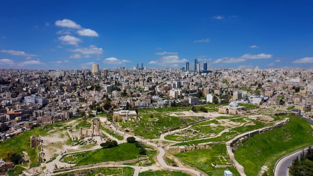 Aerial view of Amman's pale stone buildings across its hills in daylight