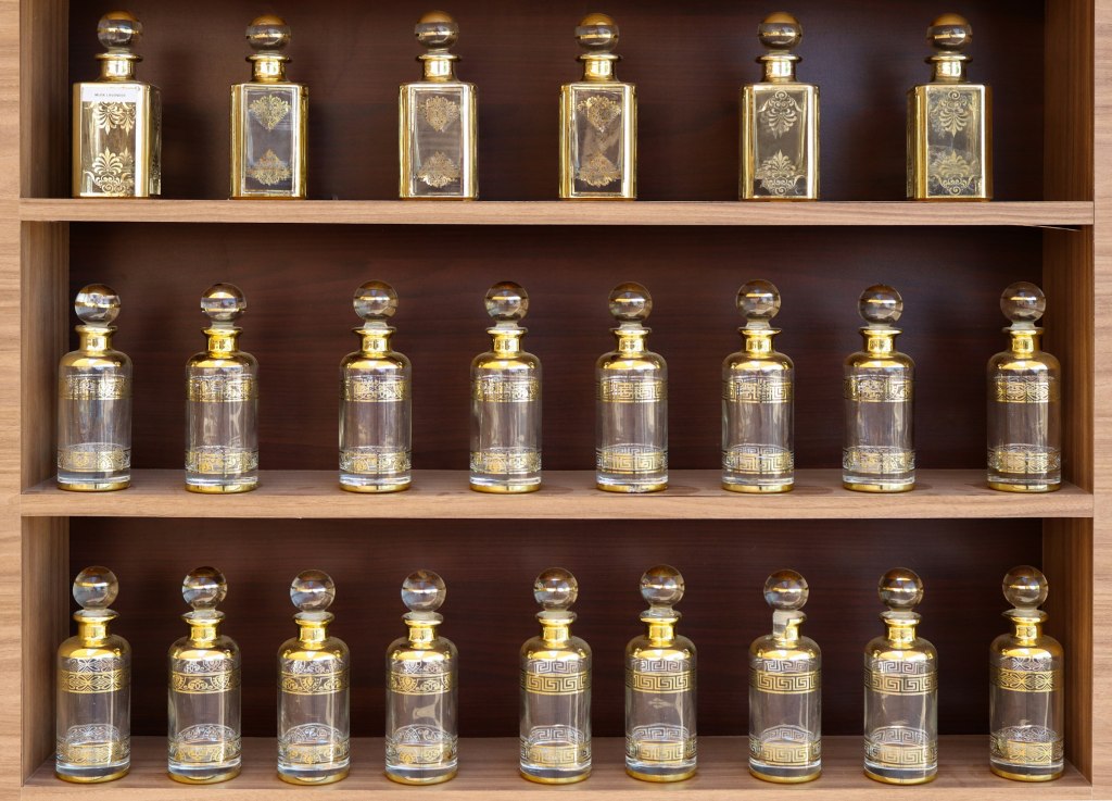 Collection of antique perfume bottles on wooden shelves, evoking Dubai's fragrance houses