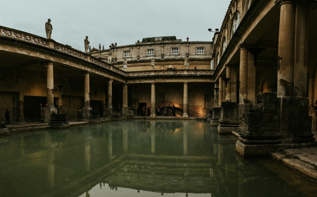 Green thermal water surrounded by golden stone colonnades in Bath, England