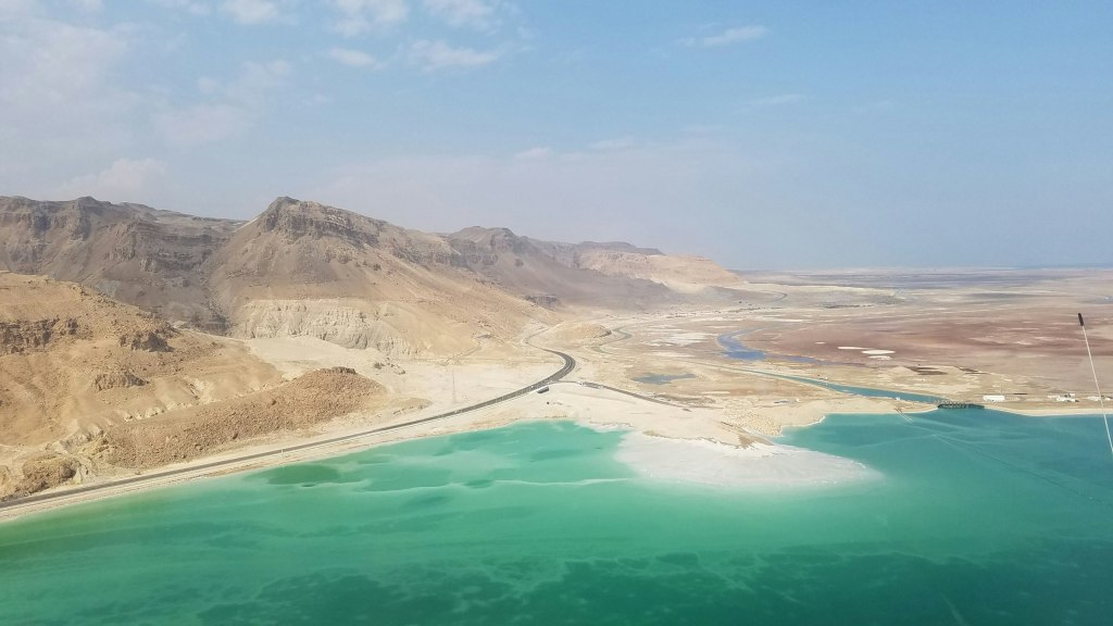 Brown mountains rising beside the still water of the Dead Sea in Jordan