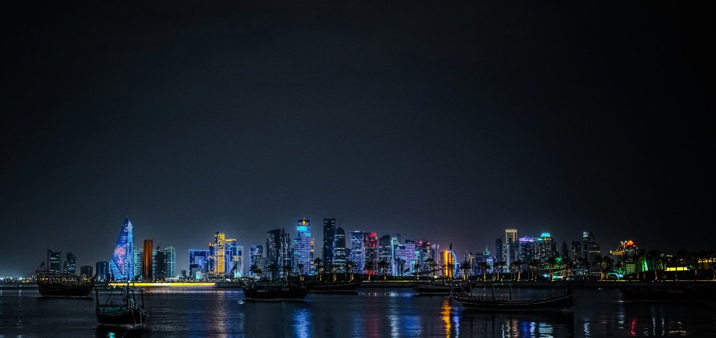 Doha skyline lit at night across the water, setting for fine dining in Qatar