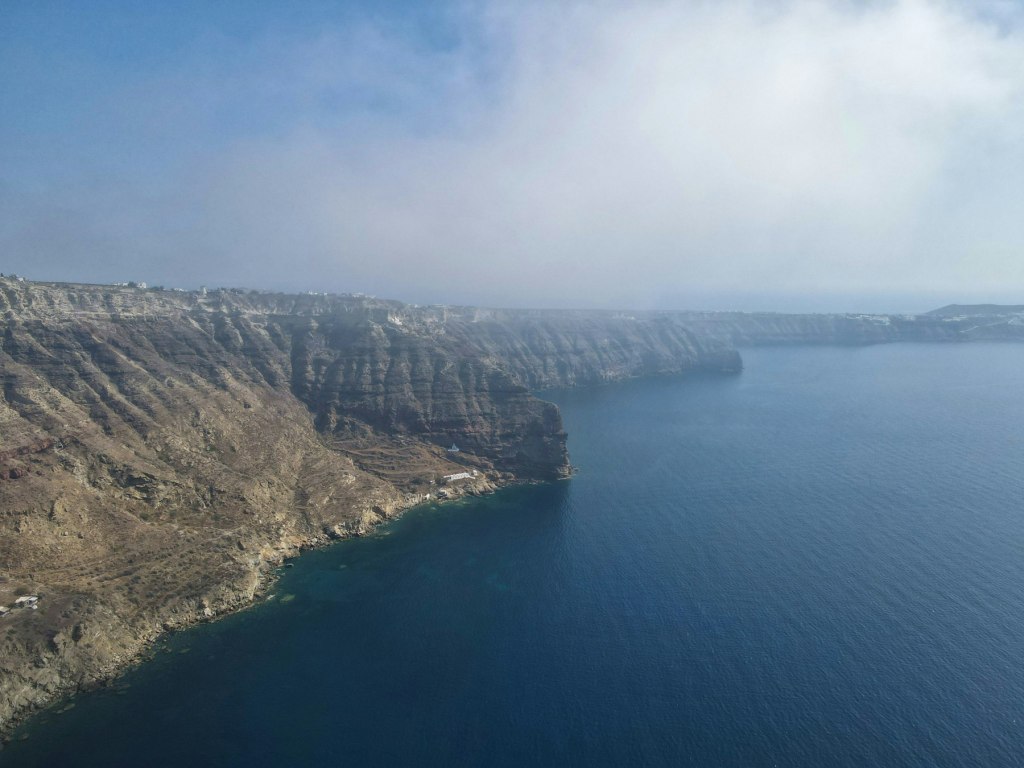 Calm blue sea beside a rugged Greek island mountain in daylight