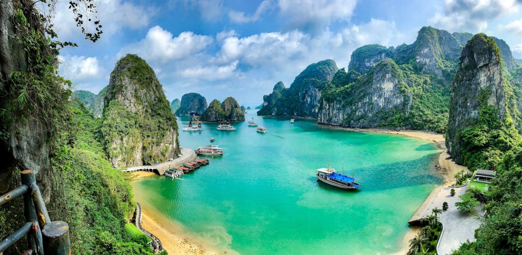 Boats on the turquoise water of Ha Long Bay among limestone karst islands in Vietnam