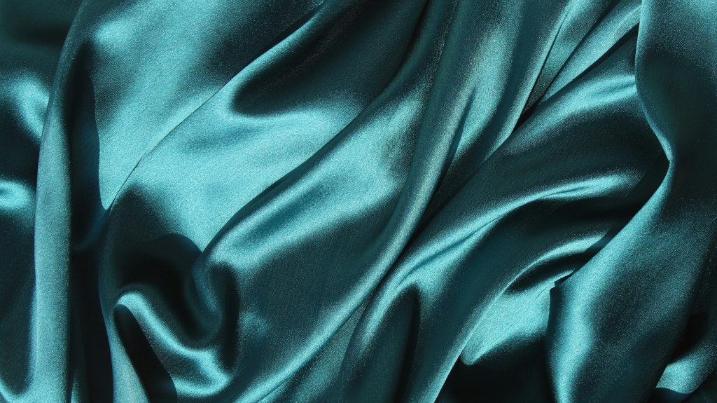 Close view of teal silk fabric, evoking the silk and tailoring shops of Hanoi