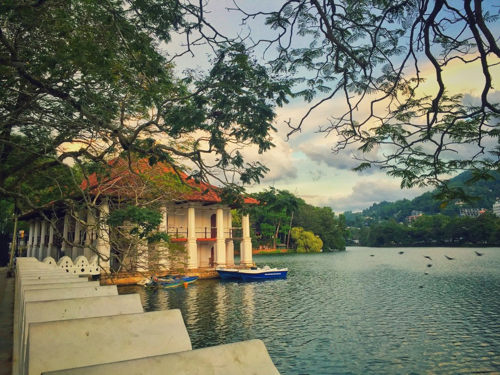 Calm waters of Kandy Lake with white buildings along the shore in Sri Lanka