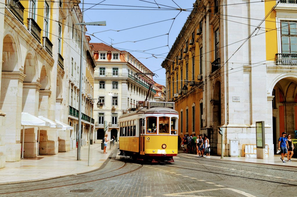 Yellow tram on a street lined with historic buildings in Lisbon, Portugal