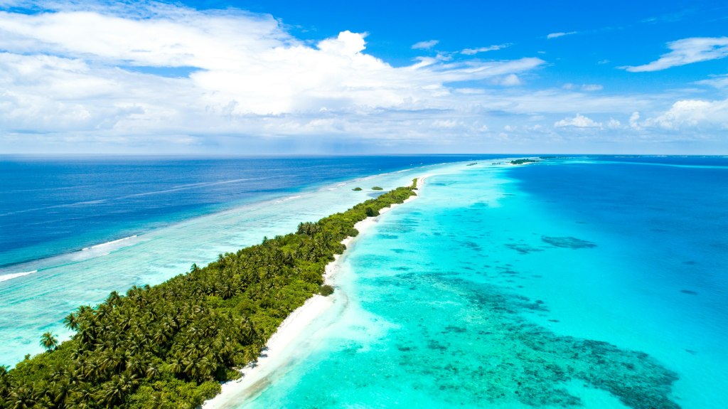 Aerial view of a tropical island ringed by turquoise water in the Maldives