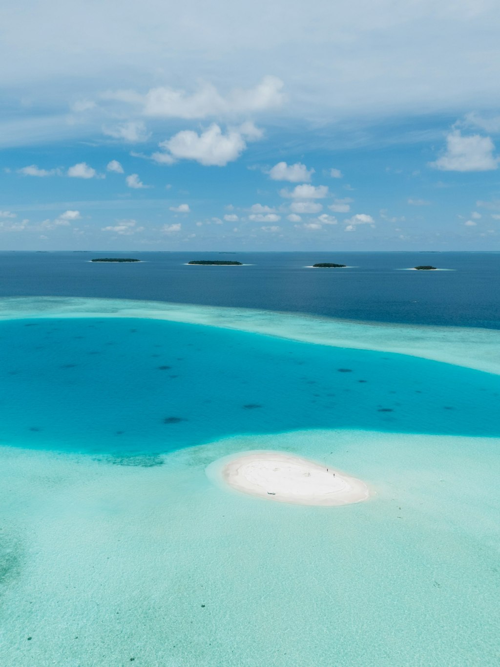 Aerial view of a small white sandbar surrounded by turquoise water