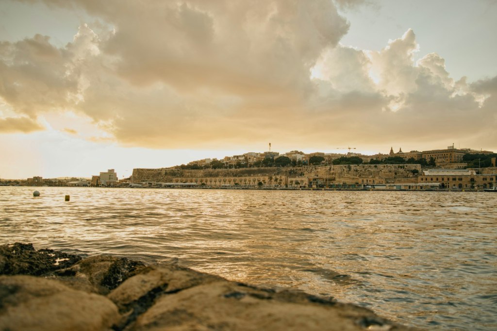 Coastal city with stone fortifications under a golden hour sky