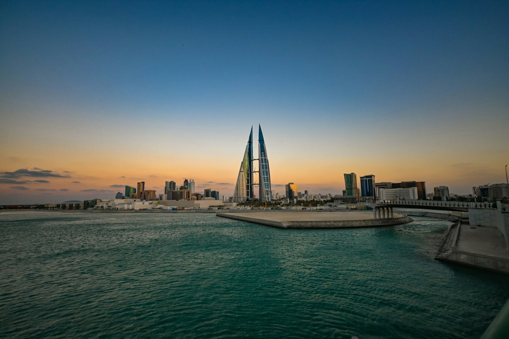 Modern Manama towers silhouetted at sunset over the water of Bahrain Bay