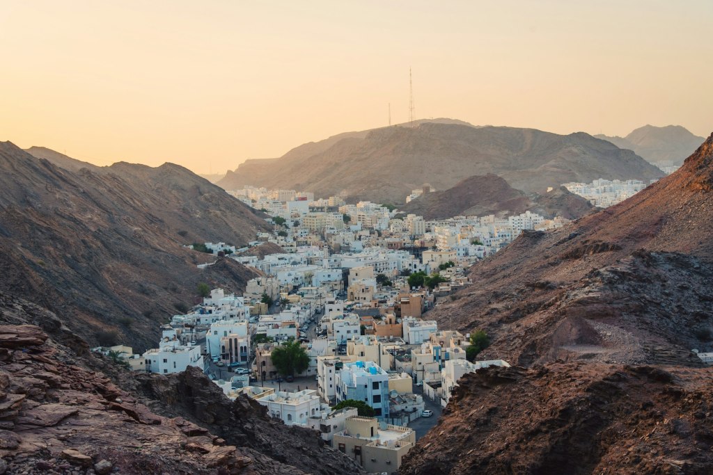 White buildings beside rocky cliffs on the coast of Muscat, Oman