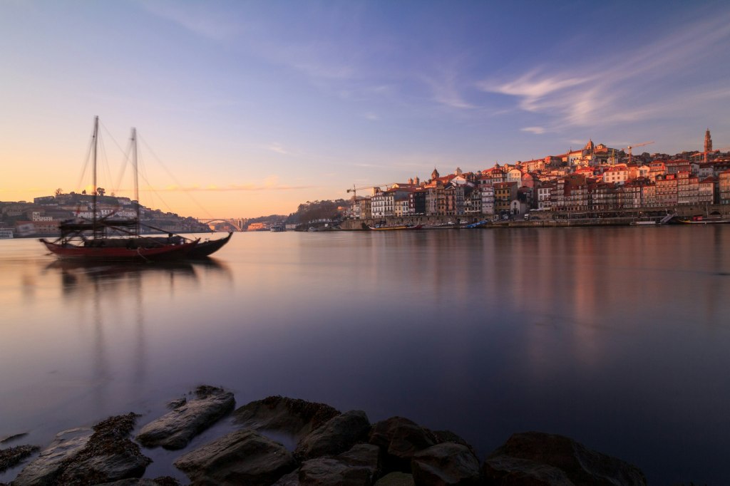 Red boat on the Douro river beside the buildings of Porto, Portugal