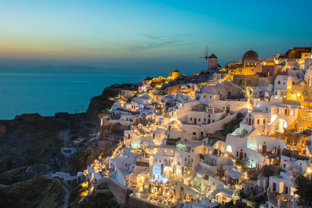 White cliffside buildings of Oia in Santorini, Greece, in warm evening light