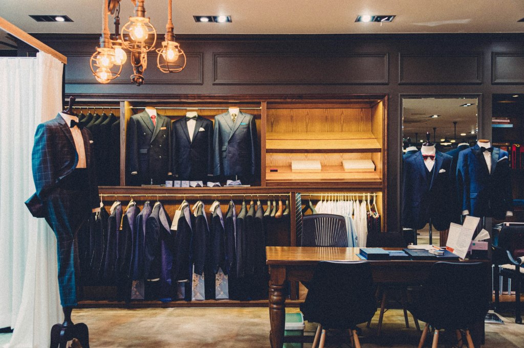 A dark tailored suit jacket on a wooden chair, evoking Savile Row bespoke tailoring in London