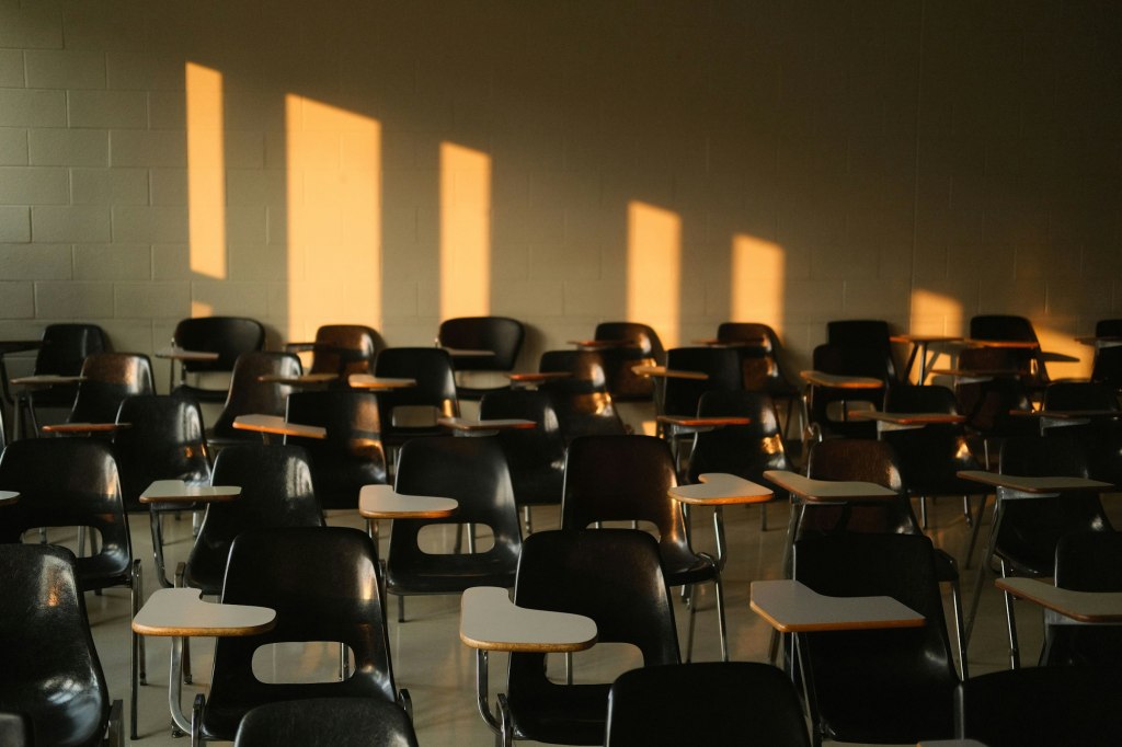 Empty university classroom with sunlight casting shadows across the desks
