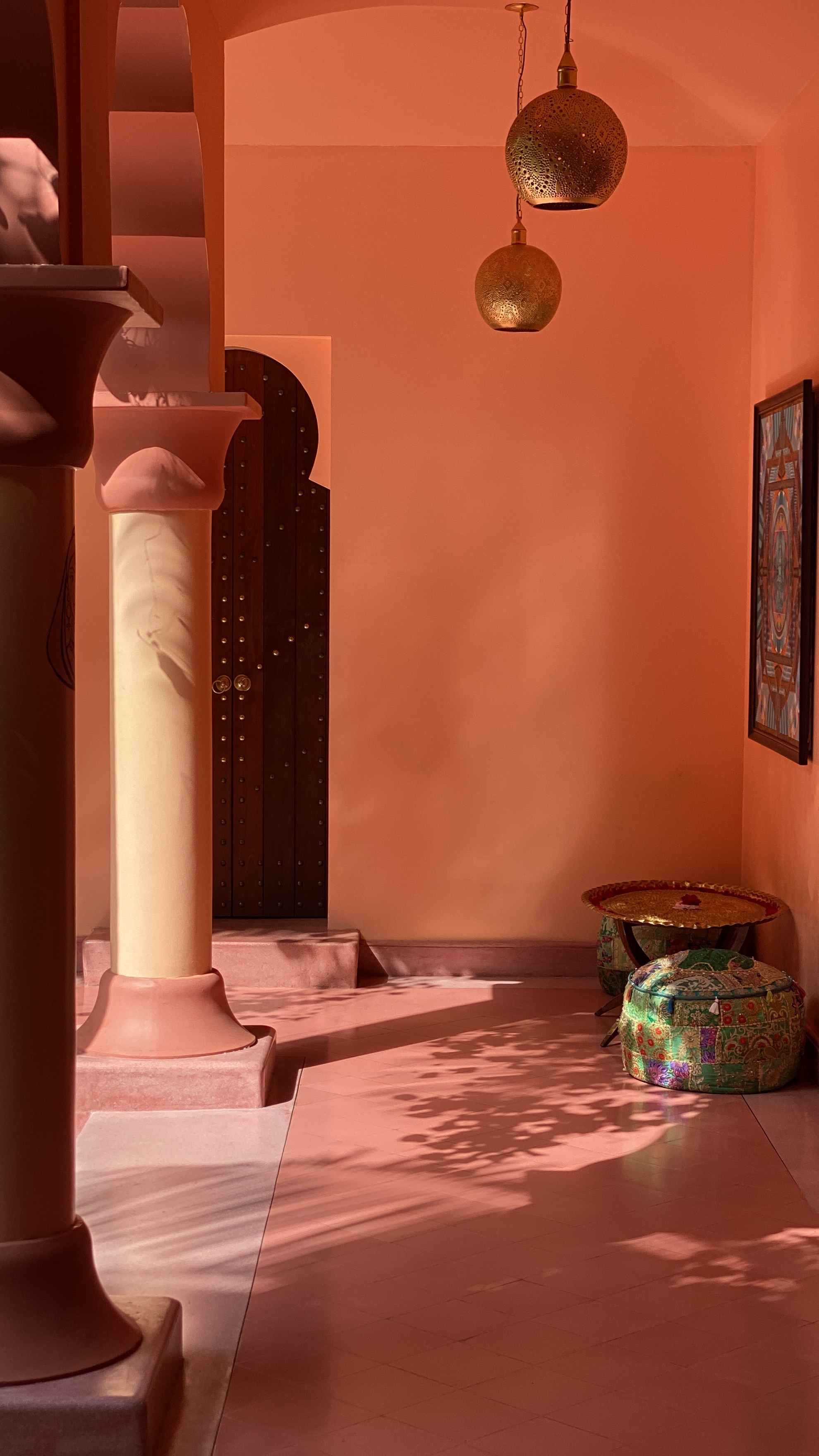 Terracotta Moroccan riad interior with brass lanterns and arched door