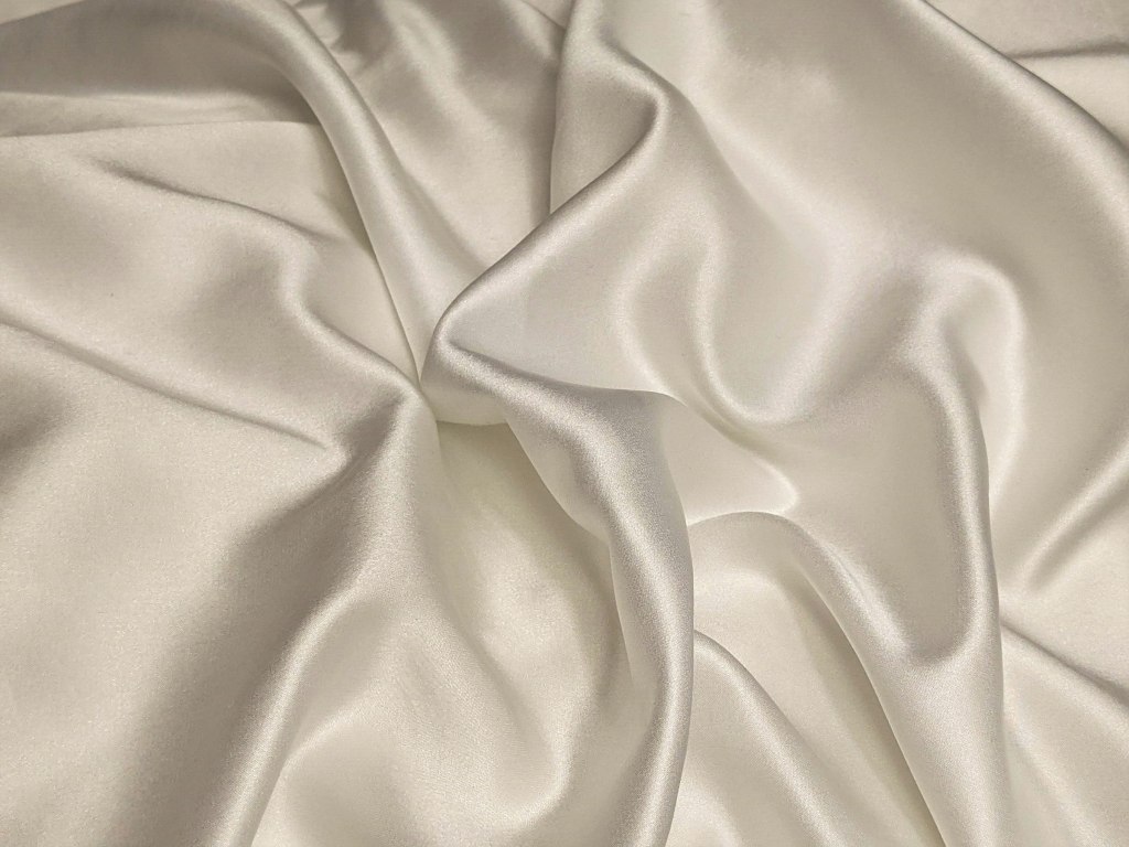 Soft folds of lustrous white silk fabric, evoking Thai silk