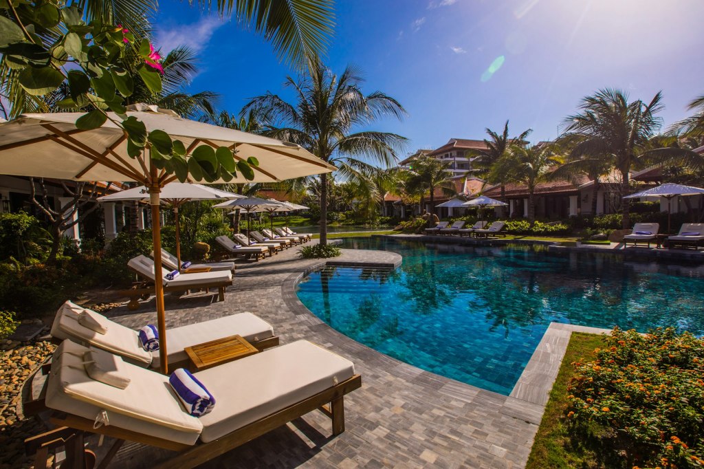 White and brown lounge chairs beside a resort swimming pool