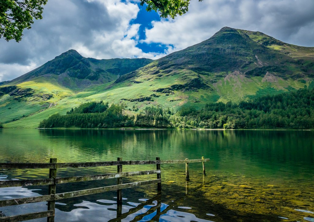 Still lake beside green mountains in the UK, a setting for cold-water swimming