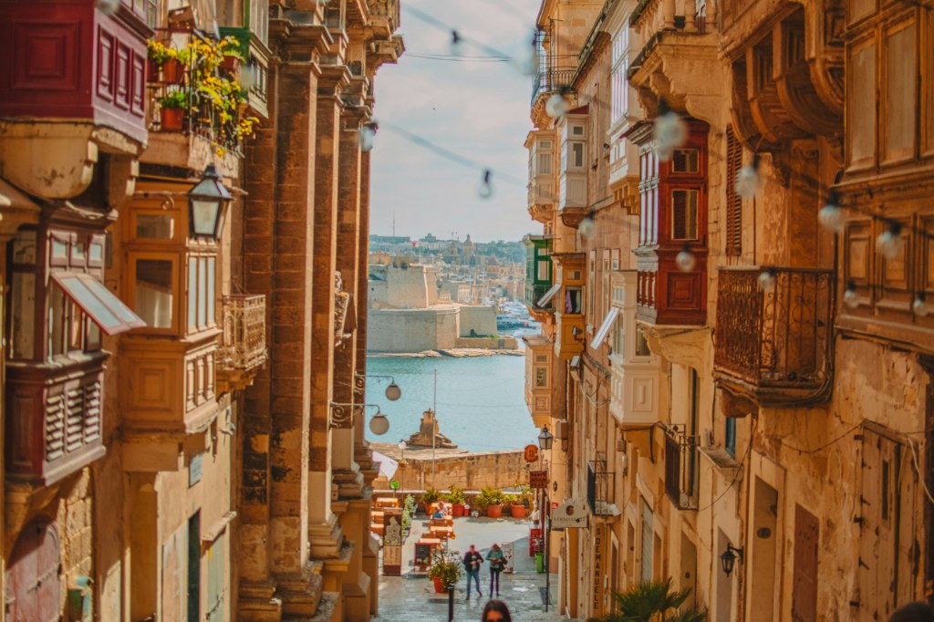 A narrow Valletta street with traditional wooden balconies overlooking the Grand Harbour in Malta
