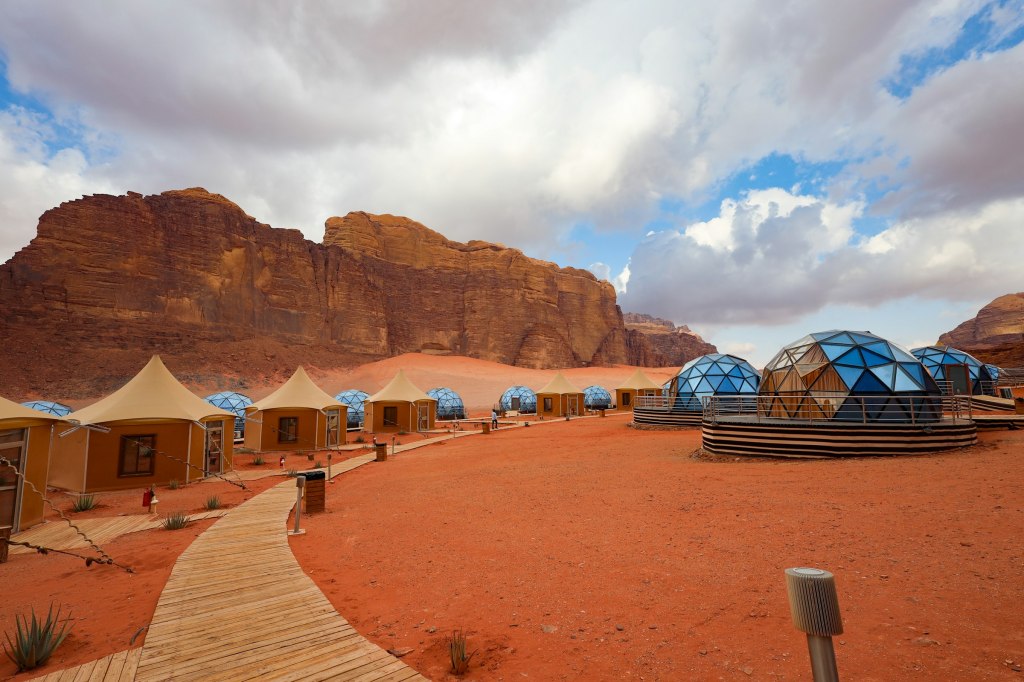 Group of desert camp tents beneath sandstone mountains in Wadi Rum, Jordan